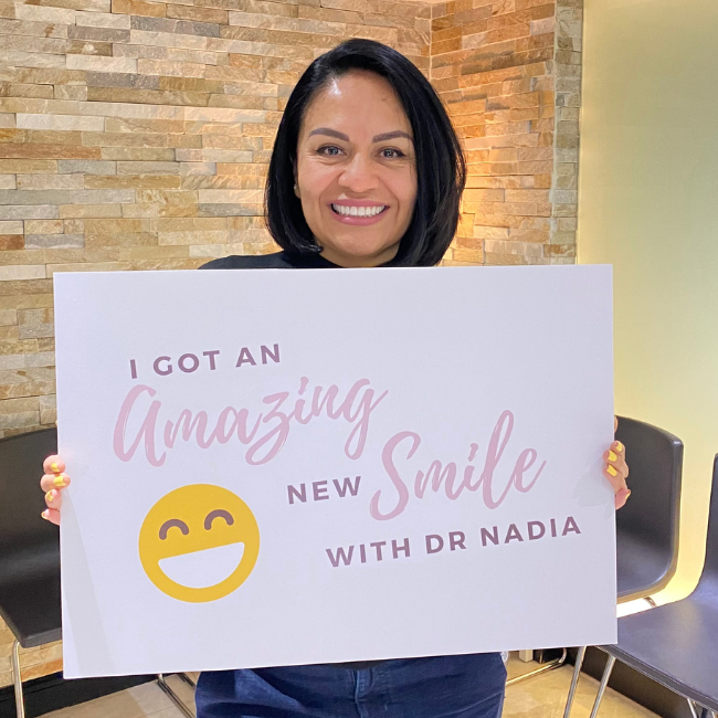 A No Limits Dental patient holding a sign about her new smile